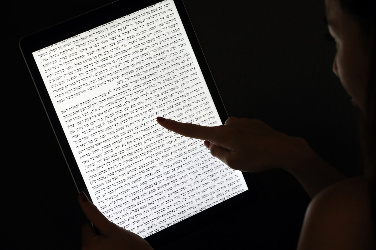 Illustrative. A woman reads a Jewish text on a tablet.