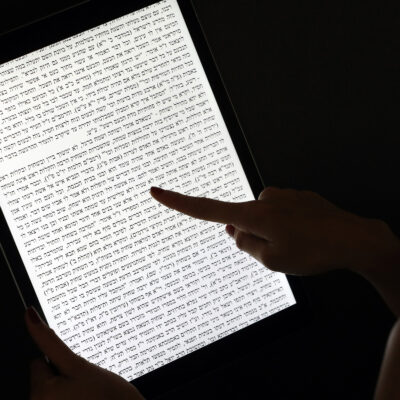 Illustrative. A woman reads a Jewish text on a tablet.