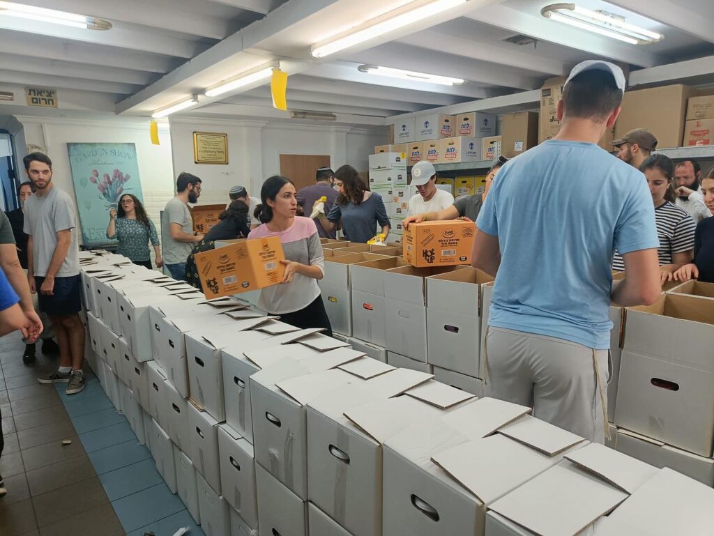 Birthright Israel participants pack boxes of food for soldiers and families in need at Beit Hatavshil, a Chabad soup kitchen in the Israeli town of Ofakim on June 25, 2024.
