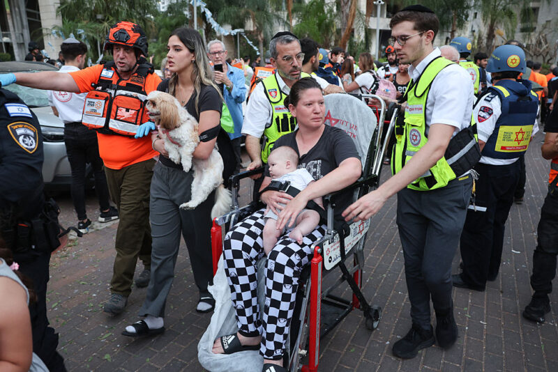 First responders attend to a woman and a baby near a damaged building following a strike by an Iranian missile in the central Israeli city of Petah Tikva, east of Tel Aviv, on June 16, 2025.